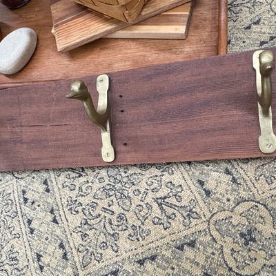 Vintage wall-mounted coat rack featuring brass duck head hooks attached to a dark wood board.