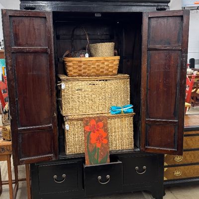 Sale Photo Thumbnail #23: Large Asian-style dark wood cabinet with double doors and three lower drawers, filled with woven storage baskets.