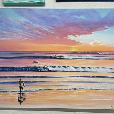 Large unframed canvas painting depicting a coastal sunset scene with surfers and ocean waves, signed in the lower right corner.