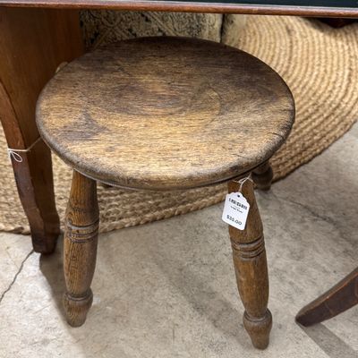 Sale Photo Thumbnail #4: Rustic three-legged wooden milking stool with turned legs and a distressed round seat.