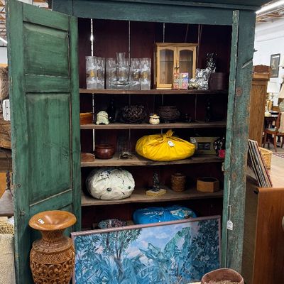Sale Photo Thumbnail #21: Rustic painted green wooden armoire filled with home decor items, glassware, and collectibles.