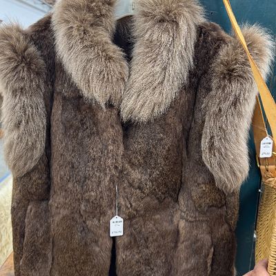 Sale Photo Thumbnail #2: Vintage brown fur vest with plush fur collar and shoulder trim details, hanging on a metal rack.