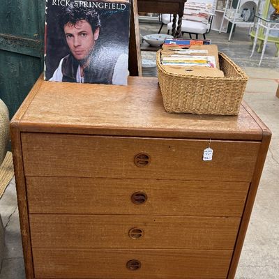 Sale Photo Thumbnail #14: Danish modern style light wood four-drawer chest with recessed round pull handles, topped with a Rick Springfield vinyl album and a wicker basket of records.