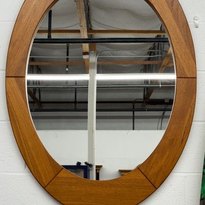 Mid-century Danish modern style oval wall mirror with a segmented teak wood frame.