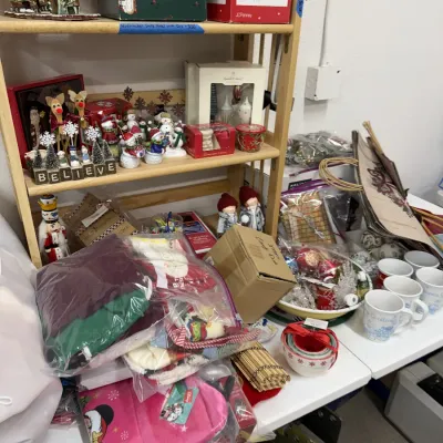 Holiday items including Christmas decor, snowmen and nutcracker figurines, boxed ornaments, festive mugs, and bagged linens.