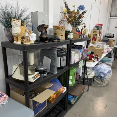Household goods including small kitchen appliances, decorative animal figurines, artificial floral arrangements, board games, and textiles.