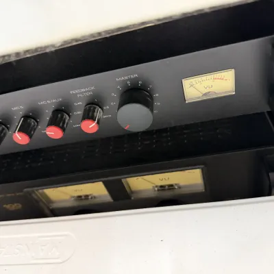 Rack-mounted professional audio equipment, including a microphone mixer with red-accented control knobs and analog VU meters.