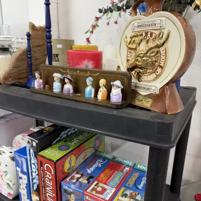 A vintage Loyal Order of Moose commemorative whiskey decanter displayed alongside miniature collectible lady bust thimbles on a wooden...