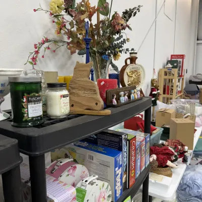Home decor items and board games, including jarred candles, faux floral arrangements, decorative tins, Cranium, and People Trivia.