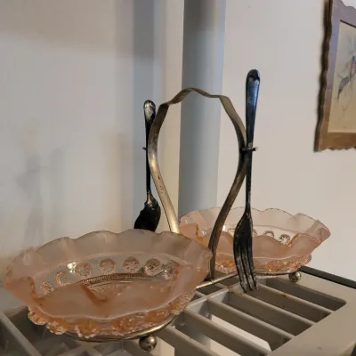 Sale Photo Thumbnail #33: Vintage double caddy condiment server featuring pink Depression glass bowls with ruffled rims and a silver-tone metal frame with matching serving utensils.