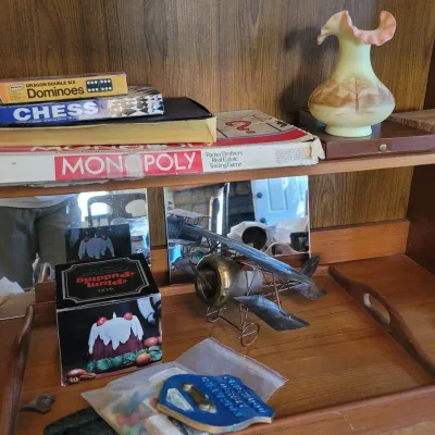Sale Photo Thumbnail #44: Classic board games like Monopoly and Chess, a metal biplane model, and a hand-painted Fenton ruffled glass vase.