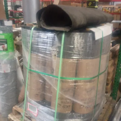 Sale Photo Thumbnail #13: Pallet of wrapped rolls of roofing felt or building paper, topped with a loose roll, secured for storage or transport in a warehouse environment.
