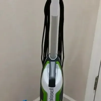 Bissell CrossWave multi-surface wet dry vacuum cleaner in green, white, and black with base tray and brush roll attachment.