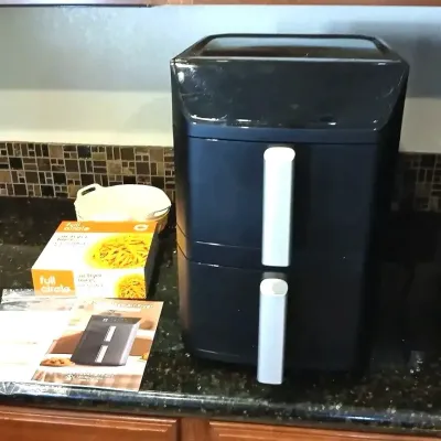 Black dual-basket air fryer, complete with user manual and a box of Full Circle air fryer liners.