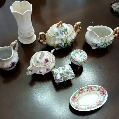 Collection of miniature vintage porcelain tableware and trinket boxes with hand-painted floral motifs and gilded accents.