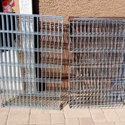 Two sets of metal wire shelving units or pet crates leaning against an exterior wall, showing minor light wear.