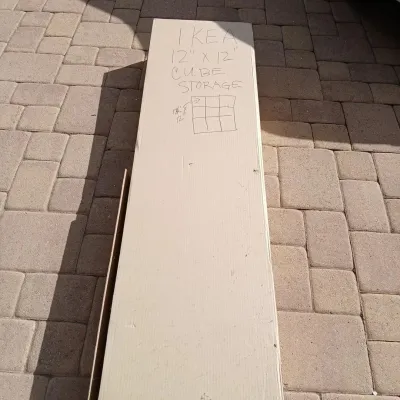 Unopened flat-pack box containing an IKEA 12" x 12" cube storage unit, labeled with handwritten notes.