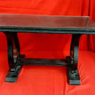 Small dark wooden trestle-style bench or table featuring curved legs, turned spindle accents, and a rectangular top.