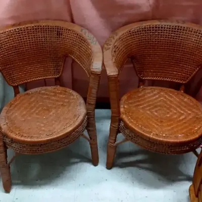 Pair of vintage woven wicker barrel-back armchairs with diamond-pattern seats and reddish-brown finish.