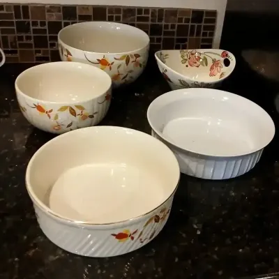 Collection of ceramic mixing and serving bowls, including several with floral and autumn leaf motifs and ribbed exterior textures.