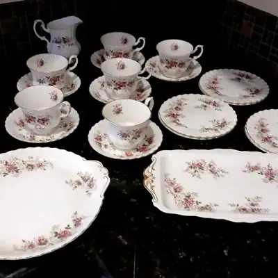 Vintage bone china tea set featuring a delicate pink rose pattern with gold trim, including teacups, saucers, side plates, a creamer, and...