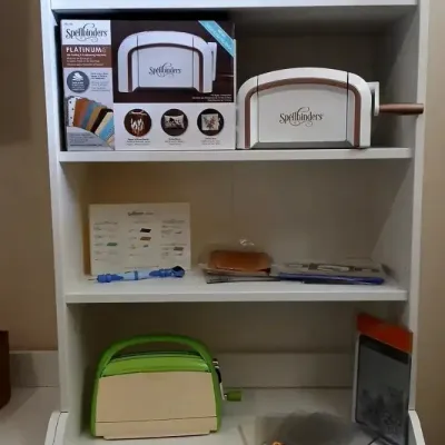 Spellbinders Platinum die cutting and embossing machine in original box, alongside a loose Spellbinders machine, green paper cutter, and...