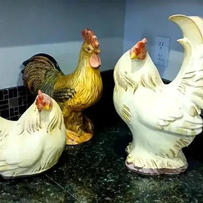 Collection of three ceramic rooster and hen figurines in cream and natural color tones.