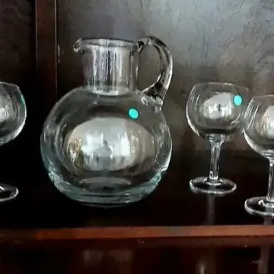 Seven-piece clear glass beverage set, including a rounded pitcher with handle and six matching stemmed wine glasses.