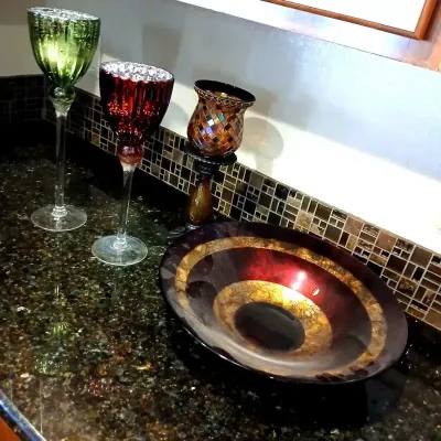 Collection of decorative glass home accents including long-stemmed goblet candle holders in green and red, a mosaic glass candle holder,...