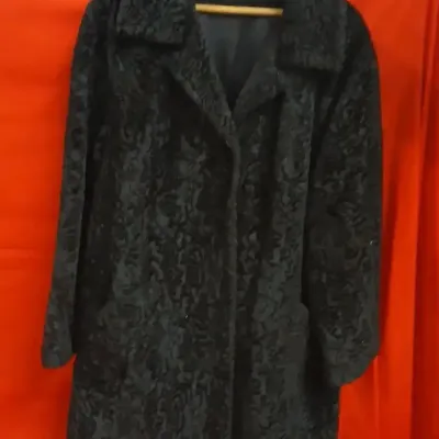 Vintage black Persian lamb fur coat featuring a wide collar, full lining, and side pockets.
