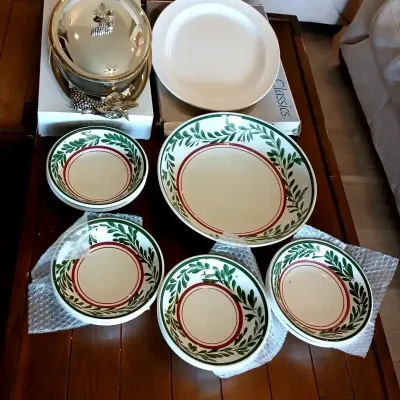 Collection of holiday table service items, including hand-painted green foliage and red rim serving bowls, a plain white charger, and an...