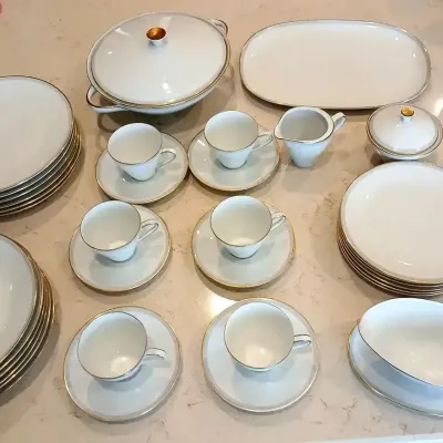 Mid-century modern Rosenthal white porcelain dinnerware set with gold trim, featuring teacups, saucers, serving platters, and covered...