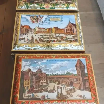 Set of three vintage Schmidt Lebkuchen tin boxes featuring detailed illustrations of historical Nuremberg scenes.