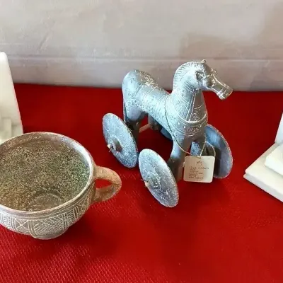Collection of decorative items, including a pair of white marble bookends, a Greek artifact-style bronze horse toy on wheels, and a...