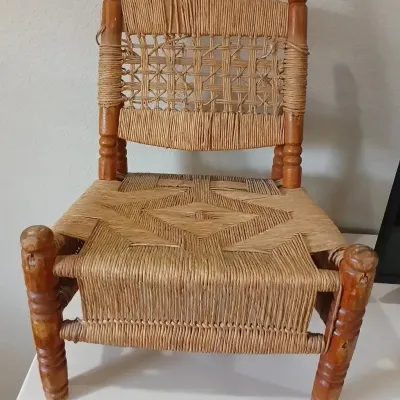 Vintage handmade wooden chair featuring an intricately woven rush seat and backrest with turned wood legs.