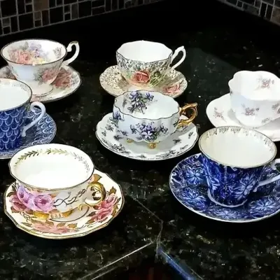 Collection of eight vintage porcelain teacup and saucer sets featuring assorted floral, scale, and gilded patterns.