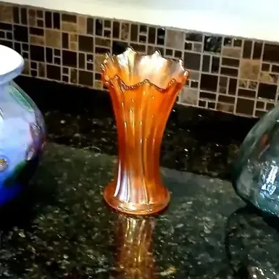 Trio of decorative glass vases, including a blue art glass vase with murrine details, an orange carnival glass vase, and a smoky gray...