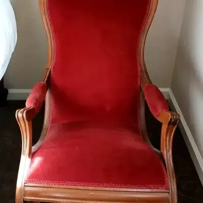Victorian-style platform rocking chair upholstered in deep red velvet with carved wooden frame details.