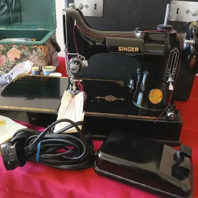 Vintage Singer Featherweight 221 electric sewing machine with foot pedal, power cord, and carrying case.