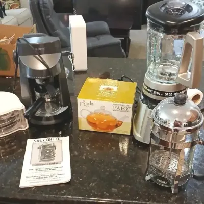 Collection of small kitchen appliances including a Mr. Coffee espresso maker, countertop blender, French press, and a boxed Primula glass...