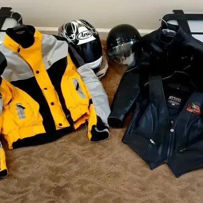 Collection of motorcycle gear including an Arai full-face helmet, a open-face helmet, yellow and black textile riding jacket, black...