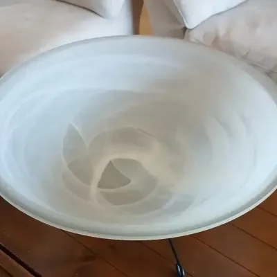 Large frosted white art glass bowl featuring swirled alabaster-style details, resting on a dark wrought iron stand.