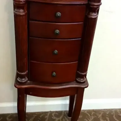 Traditional cherry-finish standing jewelry armoire featuring five drawers, fluted side columns, and cabriole legs.