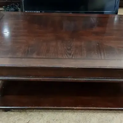 Traditional dark wood coffee table featuring a patterned veneer top and a lower display shelf.