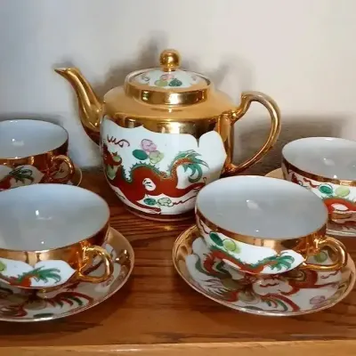 Vintage Japanese porcelain tea set featuring a teapot and four cups with saucers, decorated with hand-painted red dragons and heavy gold...