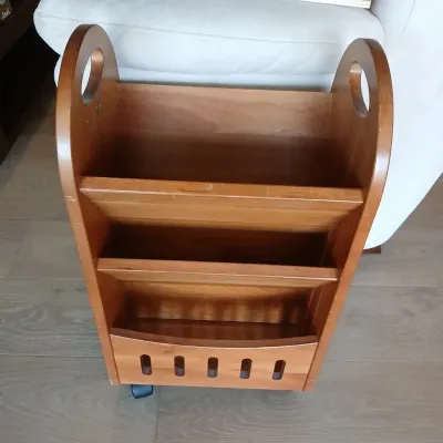 Vintage mid-century wooden rolling magazine rack and book caddy featuring cut-out handles and a tiered organizer design.