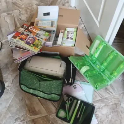 Cricut electronic cutting machine bundle, including a padded carrying case, tool kit, storage box, magazines, and various accessories.