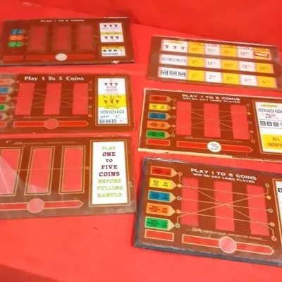 Collection of six vintage Bally slot machine glass reel belly panels displaying various payout graphics and coin instructions.