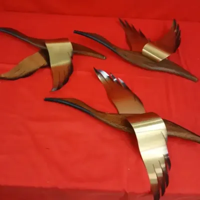 Set of three mid-century modern brass and wood flying bird wall sculptures in good vintage condition.
