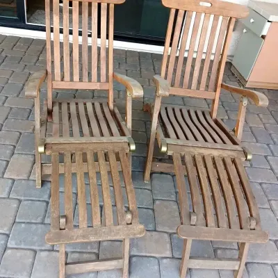 Pair of vintage teak reclining patio armchairs with detachable footrests.